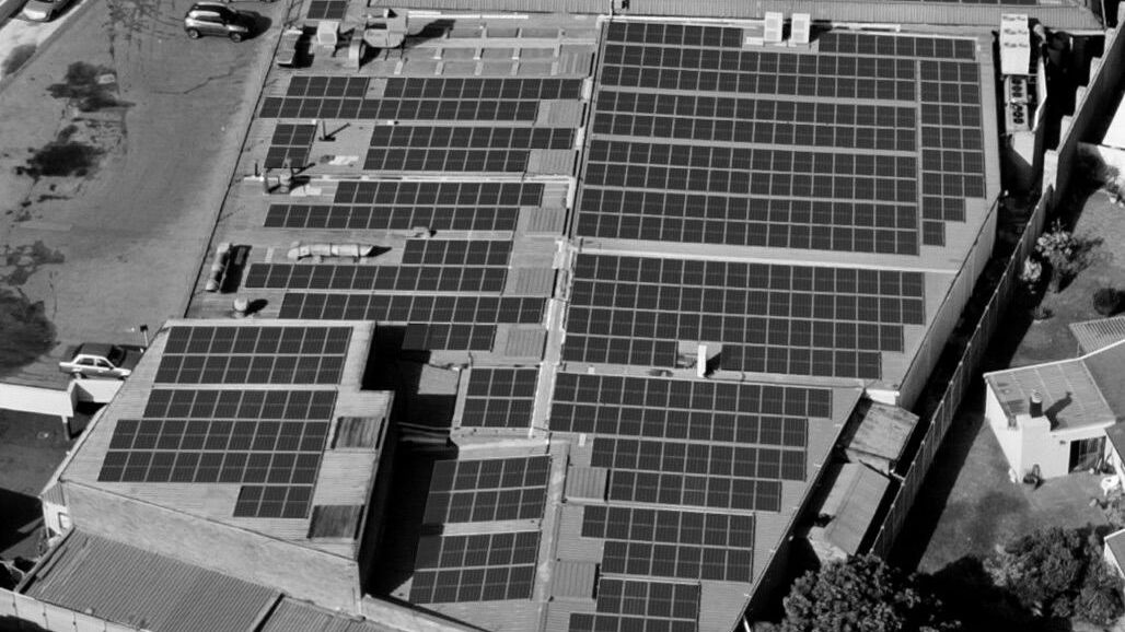 A black and white aerial photograph of solar PV panels on the roof of Pick n Pay Brackenfell.