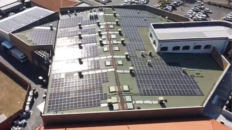 An aerial photograph of solar PV panels on the roof of a shopping centre. Queen's Corner pays less for solar energy thanks to a Decentral Energy PPA.