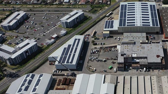 An aerial photograph of solar PV panels on the roofs of several industrial buildings. Mega Parkpays less for solar energy thanks to a Decentral Energy PPA.